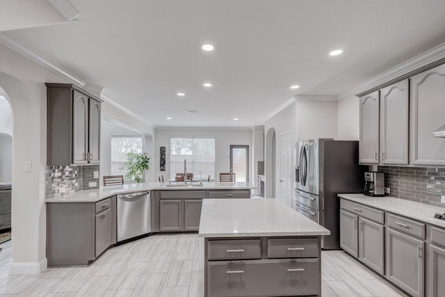 kitchen with gray cabinets, a kitchen island, appliances with stainless steel finishes, light stone counters, and kitchen peninsula