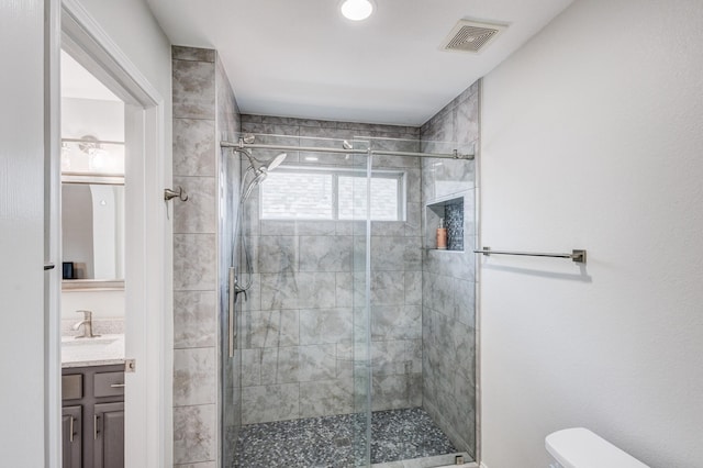 bathroom featuring vanity, a shower with door, and toilet