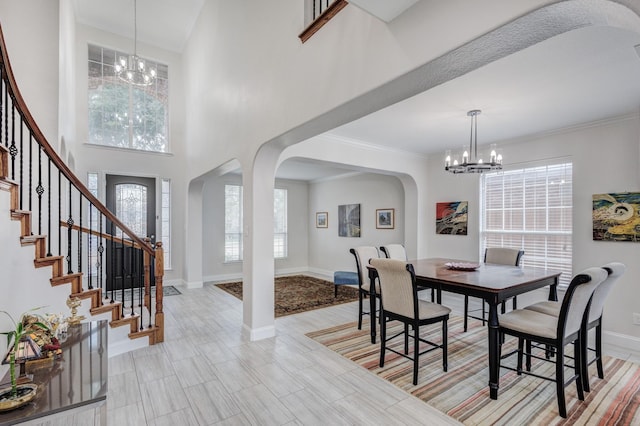 dining room featuring an inviting chandelier, a towering ceiling, and ornamental molding