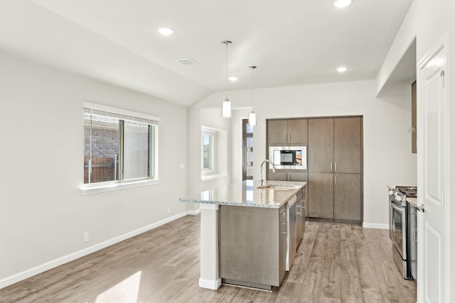 kitchen featuring pendant lighting, stainless steel appliances, a kitchen island with sink, and light hardwood / wood-style floors