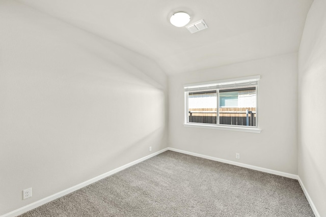 carpeted spare room featuring lofted ceiling