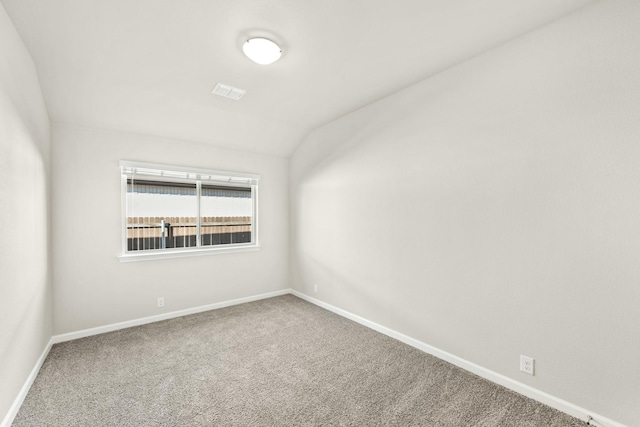 carpeted spare room featuring vaulted ceiling