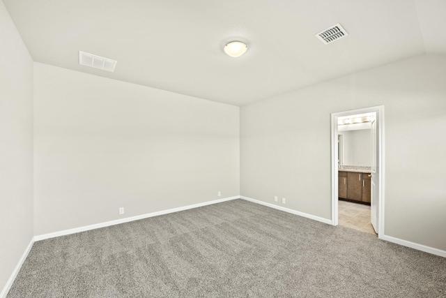 unfurnished bedroom featuring light carpet and lofted ceiling