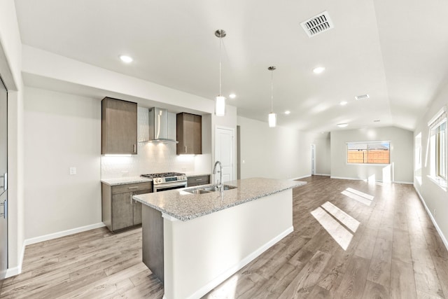 kitchen featuring pendant lighting, light hardwood / wood-style flooring, wall chimney exhaust hood, and sink