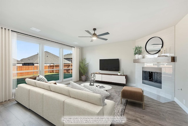 living room featuring hardwood / wood-style flooring, ceiling fan, and a fireplace