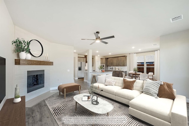 living room with a fireplace, ceiling fan, and light hardwood / wood-style flooring