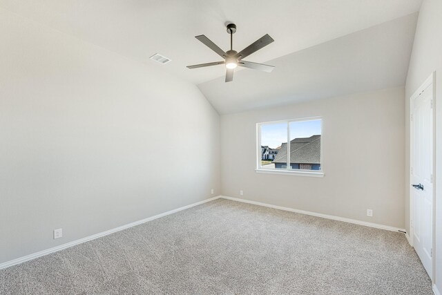 carpeted spare room with ceiling fan and vaulted ceiling