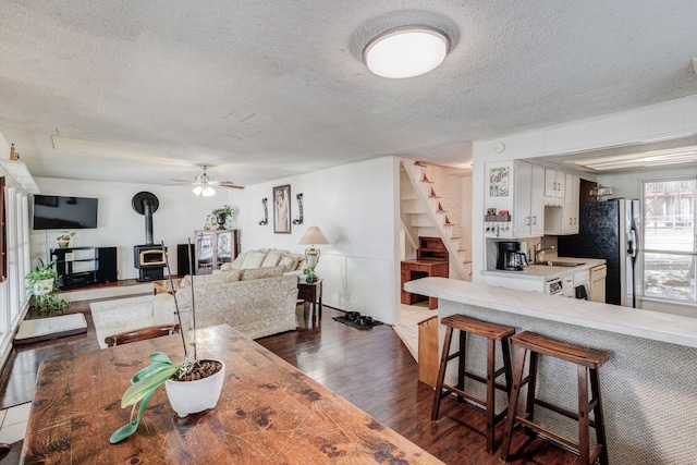 dining space with dark hardwood / wood-style floors, ceiling fan, a textured ceiling, a wood stove, and sink