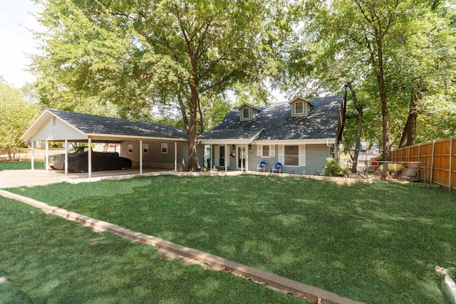 back of house with fence, driveway, a lawn, a carport, and a patio area