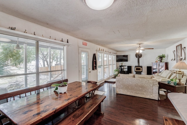 dining space with a healthy amount of sunlight, dark wood-type flooring, ceiling fan, and a textured ceiling