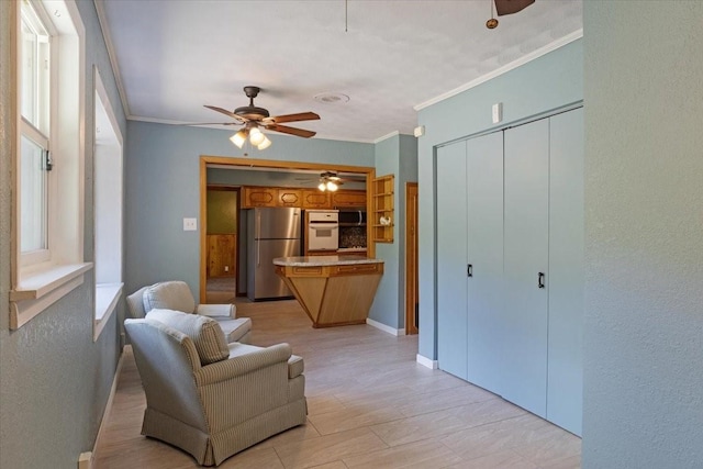 sitting room with ceiling fan and crown molding