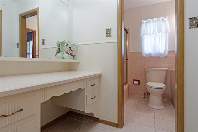 full bathroom featuring tile patterned flooring, toilet, vanity, tile walls, and shower / bath combination with glass door