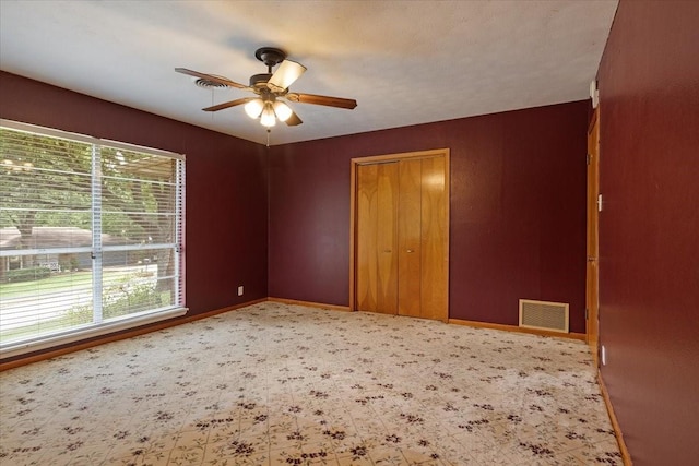 unfurnished bedroom featuring ceiling fan, a closet, and multiple windows