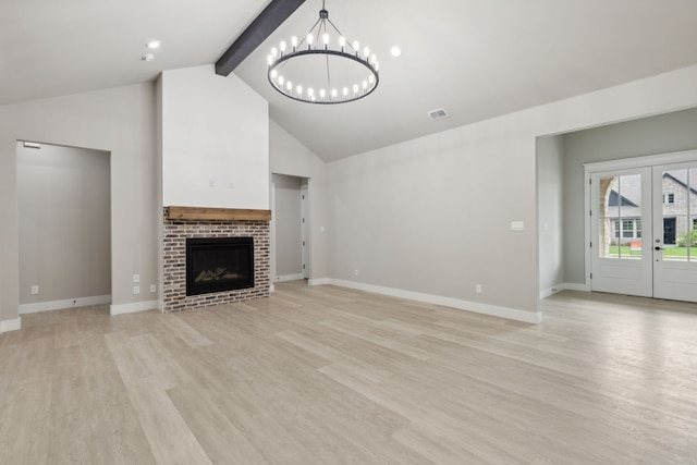 unfurnished living room featuring french doors, lofted ceiling with beams, light hardwood / wood-style flooring, a fireplace, and a notable chandelier