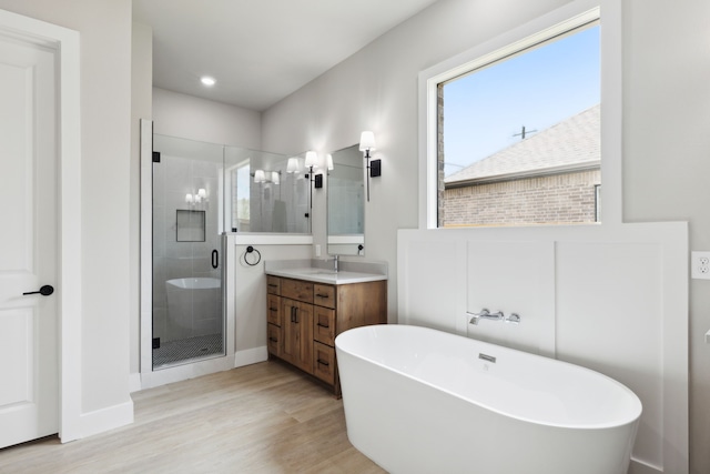 bathroom with hardwood / wood-style floors, vanity, and separate shower and tub