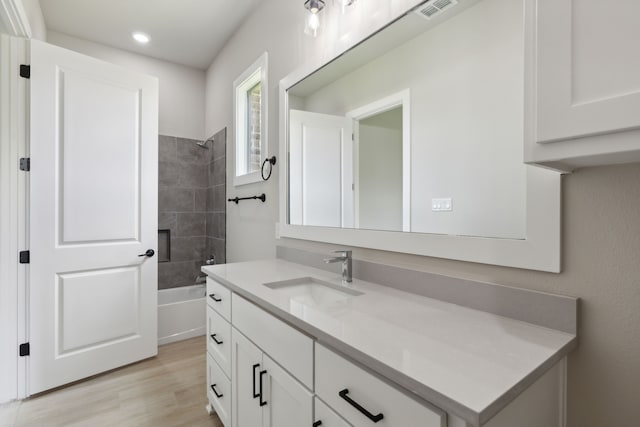 bathroom featuring hardwood / wood-style flooring, vanity, and tiled shower / bath