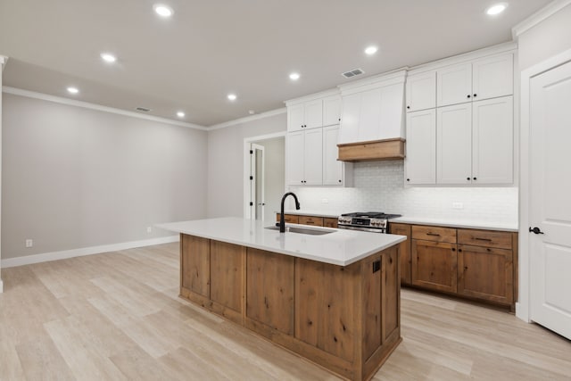 kitchen with gas stove, light hardwood / wood-style flooring, a large island, and sink