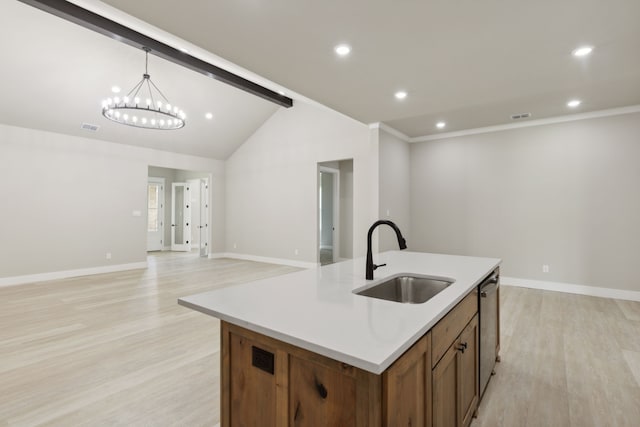 kitchen with sink, an inviting chandelier, light hardwood / wood-style flooring, decorative light fixtures, and a kitchen island with sink