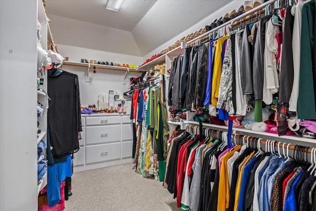 spacious closet with lofted ceiling and light colored carpet