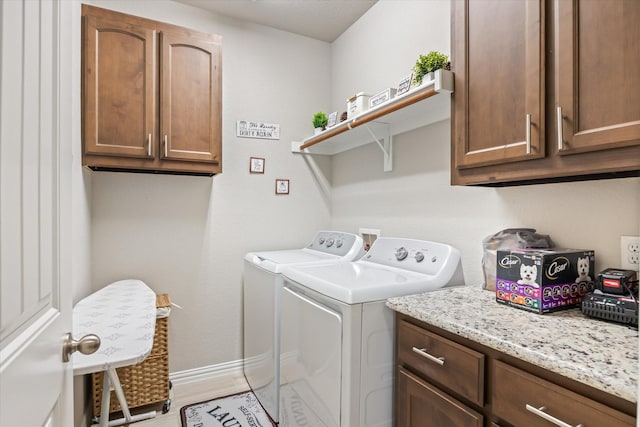 clothes washing area featuring cabinets, washer and clothes dryer, and light hardwood / wood-style flooring