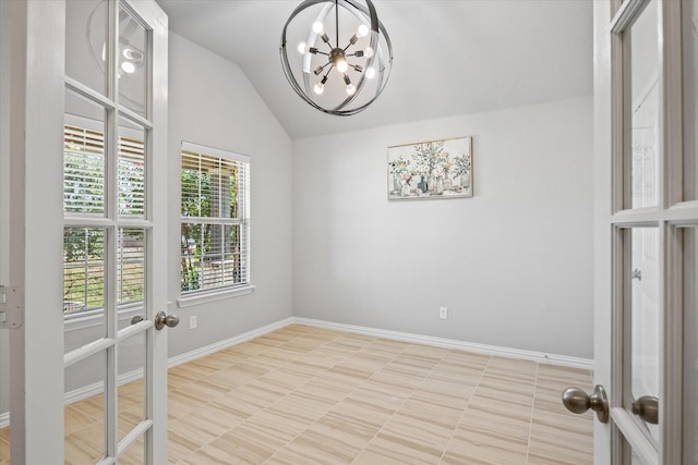 spare room featuring lofted ceiling, french doors, and a chandelier