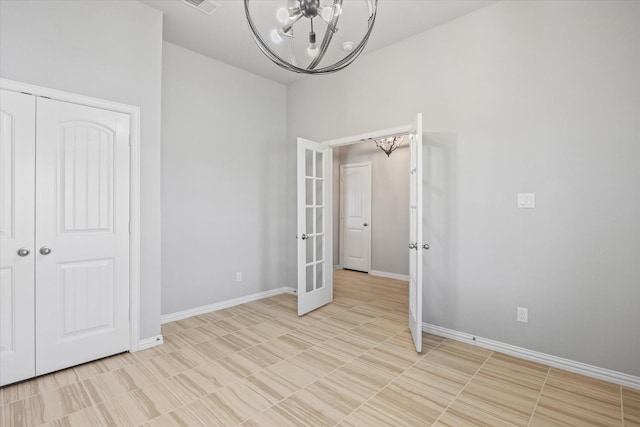 unfurnished bedroom featuring french doors, a chandelier, and a closet