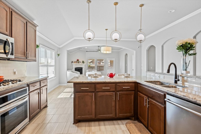 kitchen with sink, light stone counters, appliances with stainless steel finishes, pendant lighting, and decorative backsplash