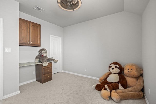 interior space featuring built in desk, vaulted ceiling, and light carpet