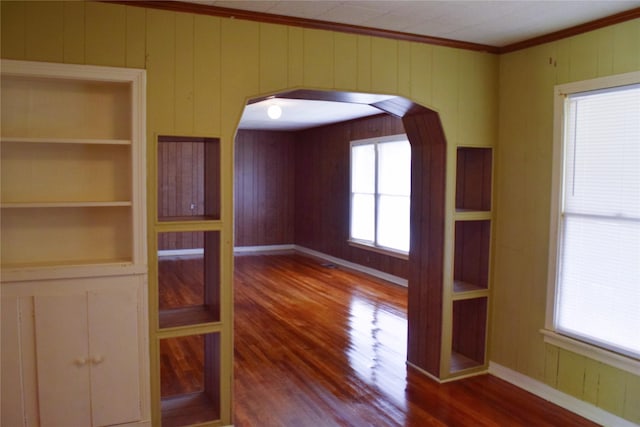 unfurnished dining area with hardwood / wood-style floors, built in shelves, ornamental molding, and a wealth of natural light