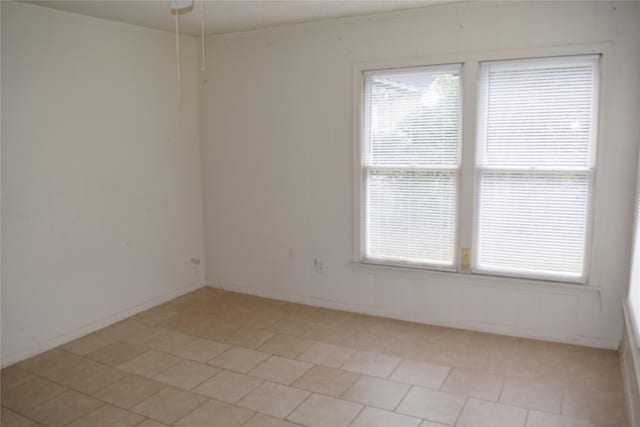 tiled empty room featuring crown molding