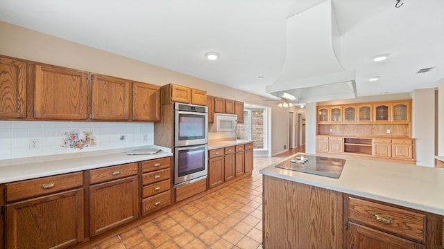 kitchen featuring premium range hood, black electric stovetop, backsplash, and stainless steel double oven