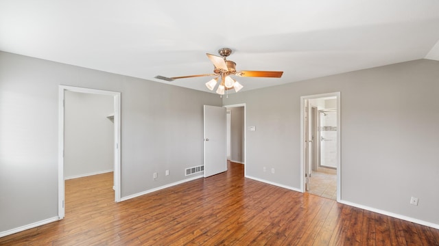 unfurnished bedroom featuring ensuite bath, hardwood / wood-style flooring, ceiling fan, a spacious closet, and a closet