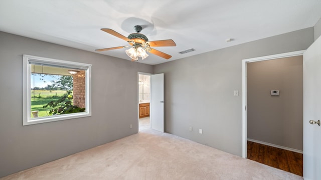 empty room featuring ceiling fan and light colored carpet