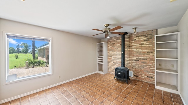 unfurnished living room featuring built in features, tile patterned floors, ceiling fan, and a wood stove