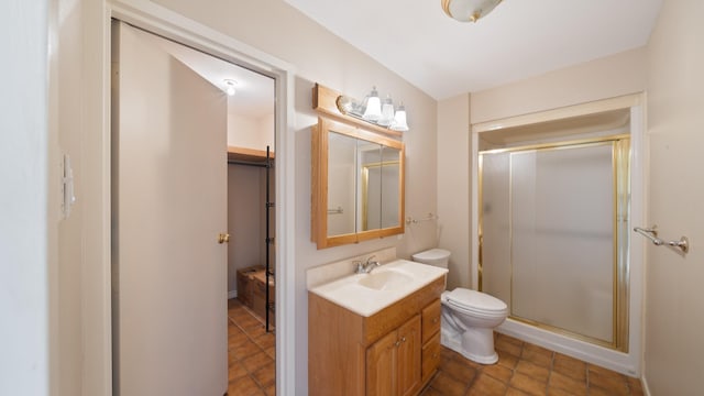 bathroom featuring a shower with door, vanity, and toilet