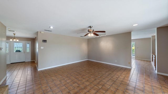 spare room featuring ceiling fan with notable chandelier and dark tile patterned flooring