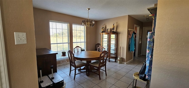 dining area with light tile patterned floors, a notable chandelier, and a textured ceiling