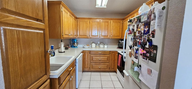 kitchen featuring white appliances, sink, and light tile patterned floors