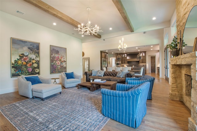 living room with a fireplace, hardwood / wood-style floors, beamed ceiling, and a chandelier