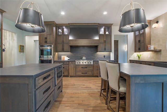 kitchen with dark brown cabinets, a kitchen island, appliances with stainless steel finishes, and tasteful backsplash