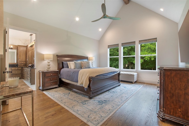 bedroom featuring ceiling fan, light hardwood / wood-style floors, high vaulted ceiling, and ensuite bath