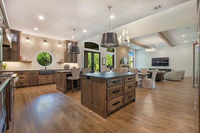 kitchen featuring a breakfast bar, beam ceiling, a kitchen island, and hanging light fixtures