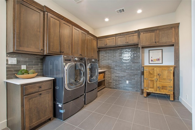 laundry room featuring cabinets, light tile patterned floors, and washing machine and clothes dryer