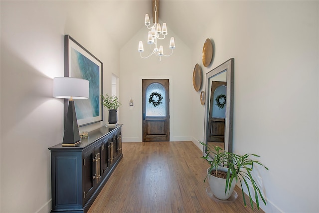 foyer entrance with vaulted ceiling with beams, hardwood / wood-style flooring, and a notable chandelier