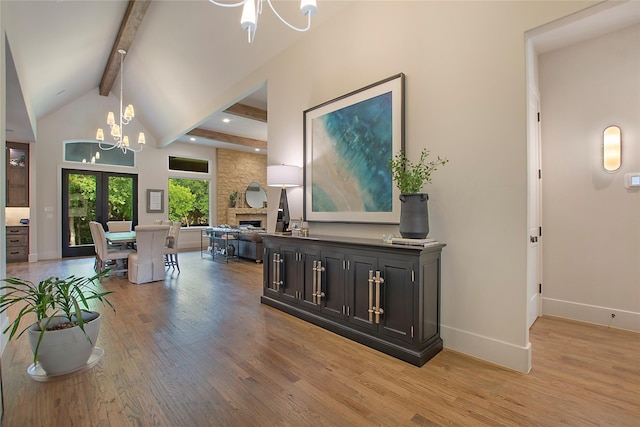 hallway featuring beam ceiling, french doors, an inviting chandelier, high vaulted ceiling, and light hardwood / wood-style floors