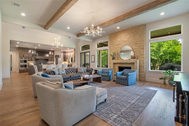 living room featuring a fireplace, beamed ceiling, light hardwood / wood-style flooring, and a notable chandelier