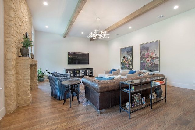 living room with beam ceiling, a stone fireplace, an inviting chandelier, and hardwood / wood-style flooring