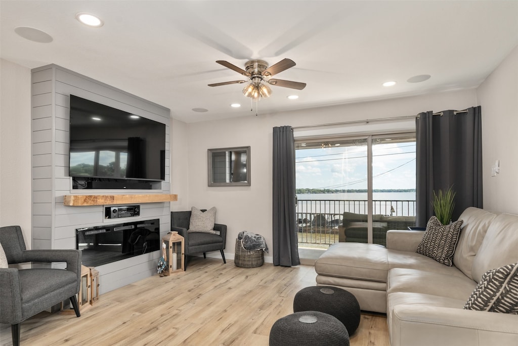 living room featuring a fireplace, ceiling fan, and light wood-type flooring