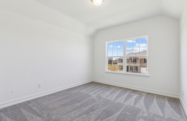 carpeted spare room featuring vaulted ceiling