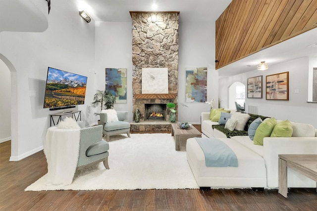 living room with a stone fireplace and dark hardwood / wood-style floors